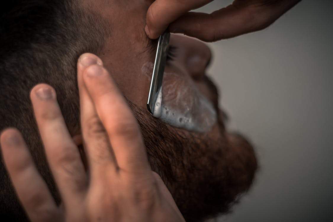 Un homme entrain de se faire tailller la barbe au ciseau